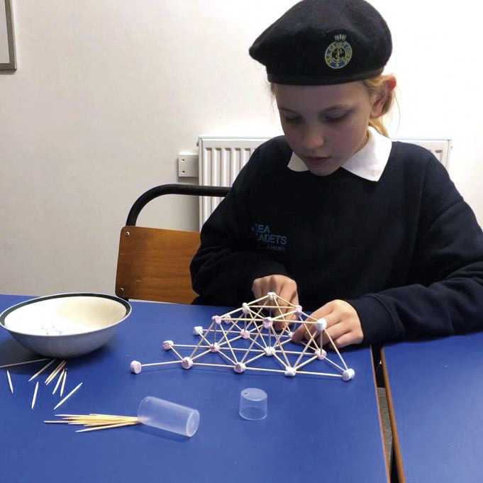 A cadet concentrates on building a geodesic shape