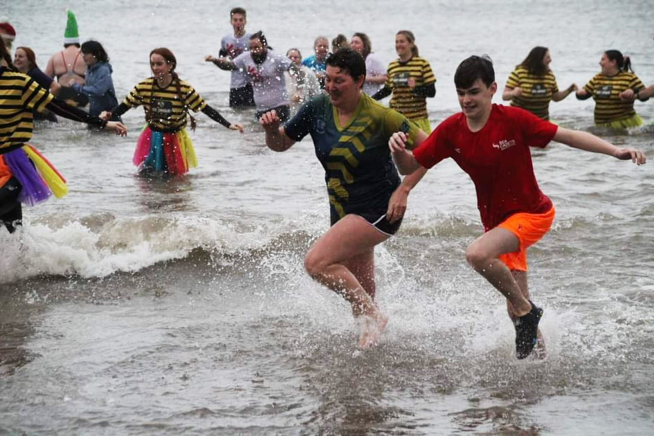 Swimmers run into the cold sea on New Year's Day