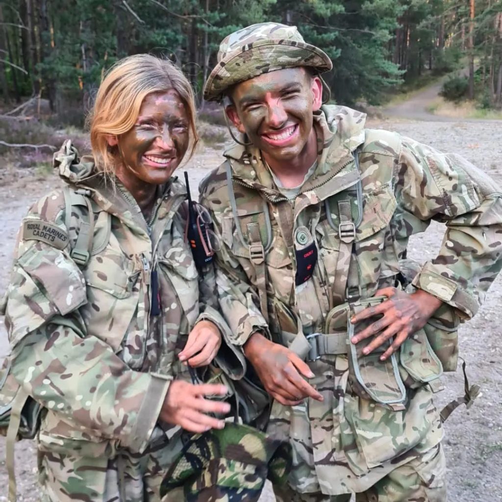 Royal Marines cadets with smiling muddy faces wearing fatigues