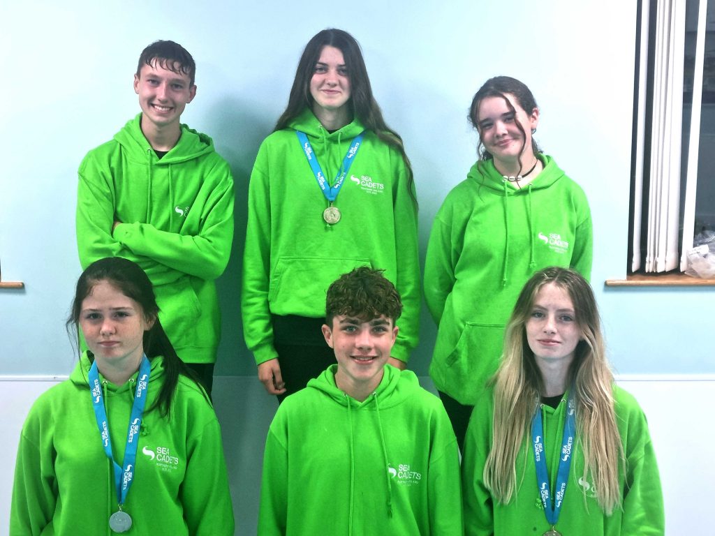 Cadets wearing bright green sweatshirts pose for a photo after winning at the regatta