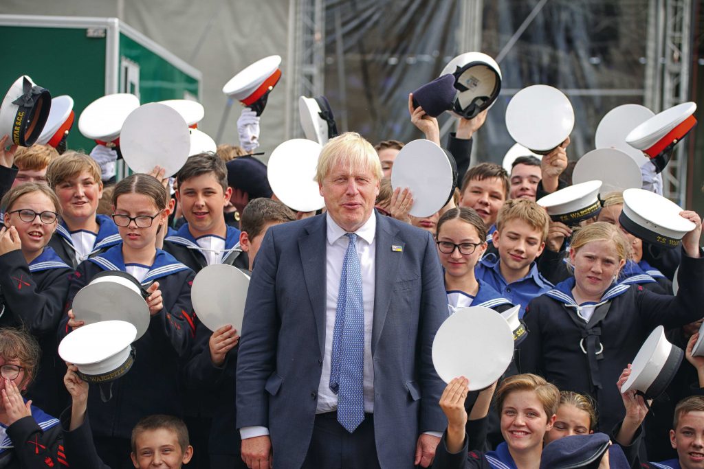 Boris Johnson with sea cadets holding their hats aloft