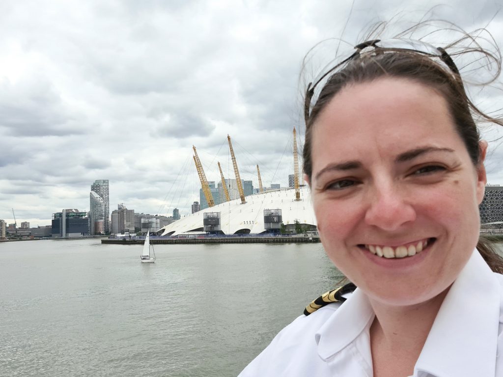 a close-up photo of caz in uniform, with a port in the background