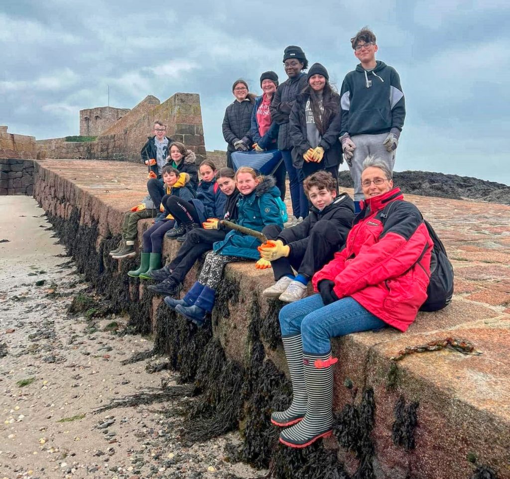 Cadets and volunteers sit on the sea wall after a beach clean in Jersey