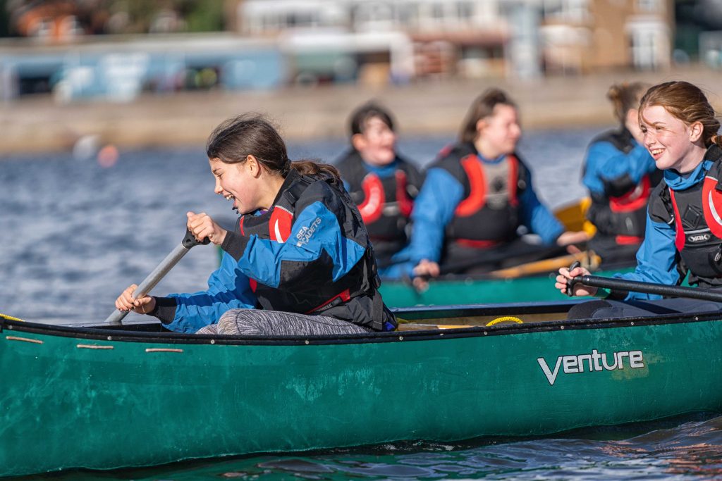 female cadets laugh while they're rowing 