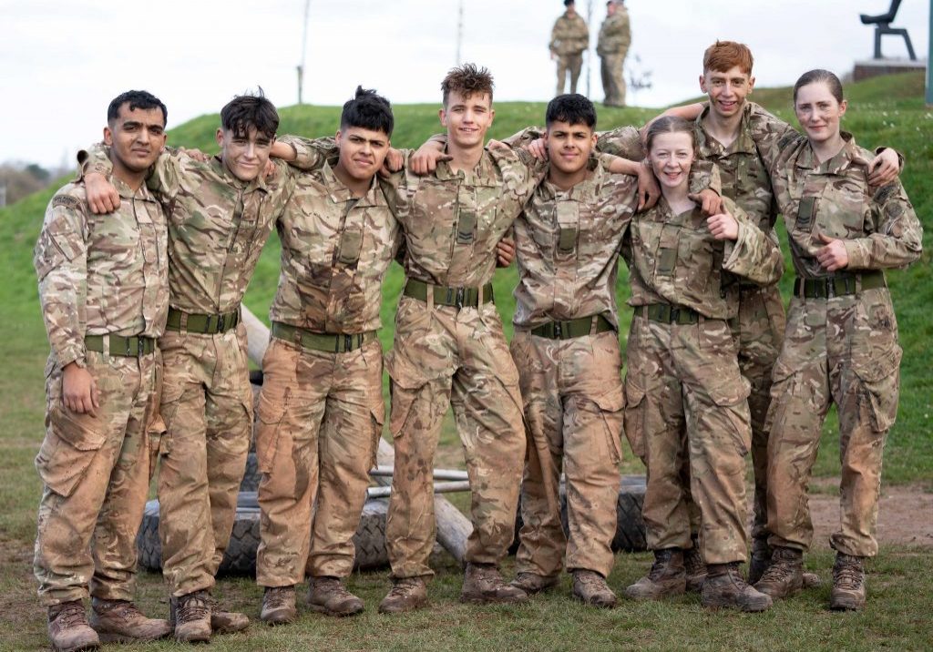 a row of cadets pose for the camera with their arms on each other's shoulders