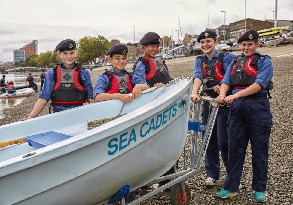 Young cadets pull a boat up to the beach